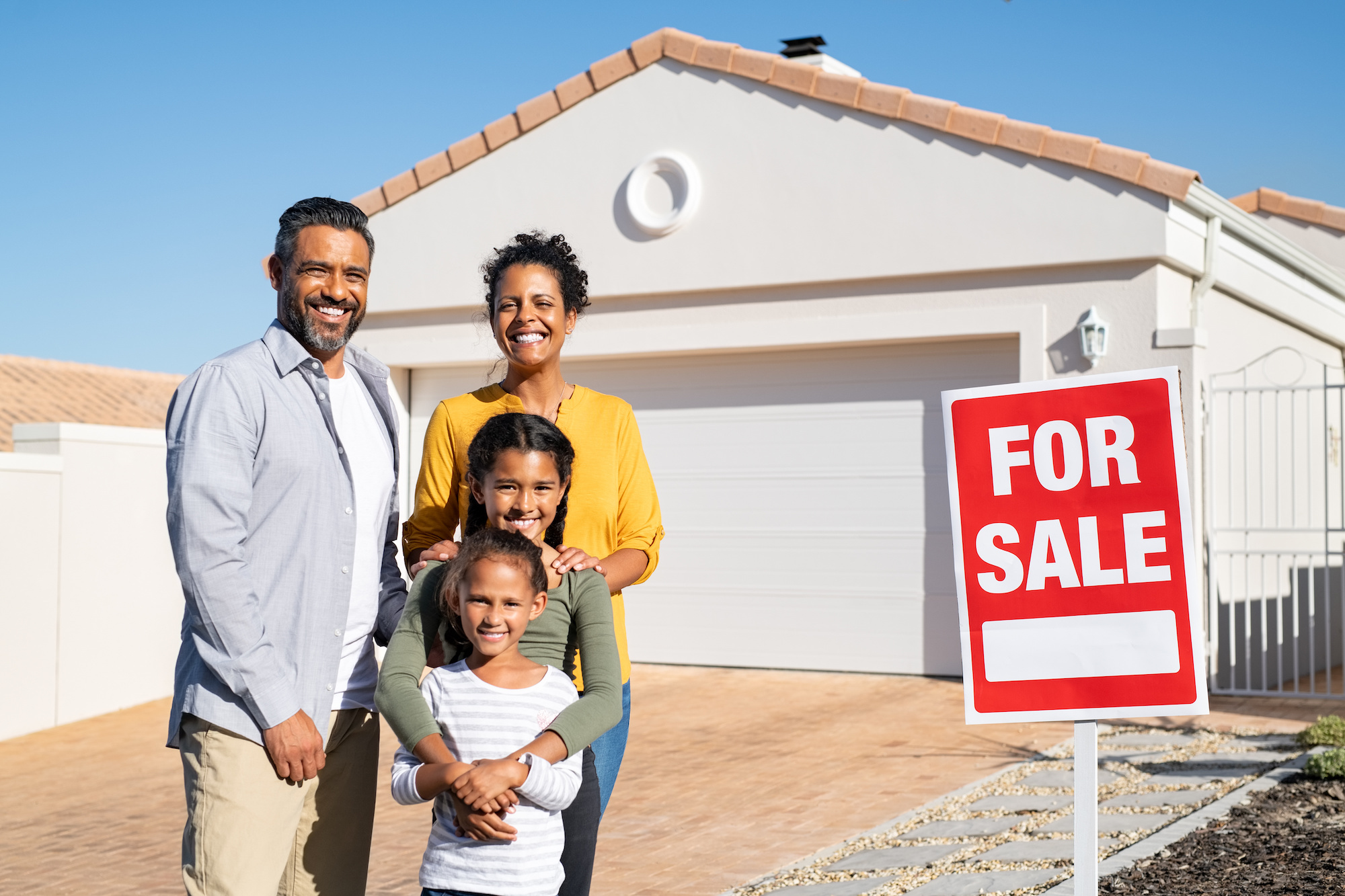 A Hispanic family standing in front of an El Paso home they recently listed for sale.