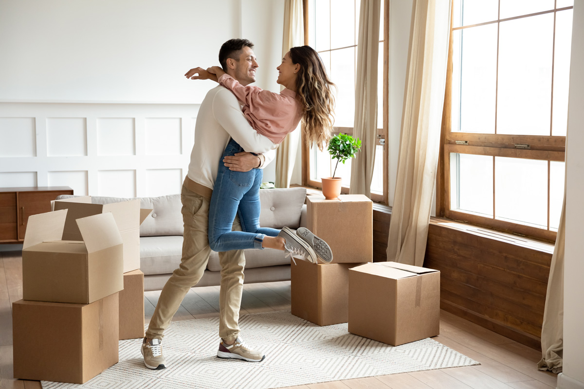 A couple hugging surrounded by moving boxes in their new El Paso home.
